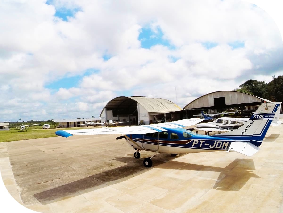 Monomotor Cessna PT-JDM da Piquiatuba no pátio da base, com os hangares da empresa ao fundo — foto publicada no site da operadora